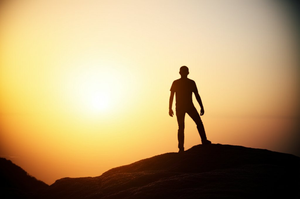 Lone figure on rugged clifftop at dawn, silhouetted against a vibrant sunrise, symbolizing strength and resilience.